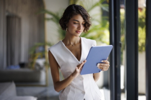 Person in white suite in open, spacious office using a tablet